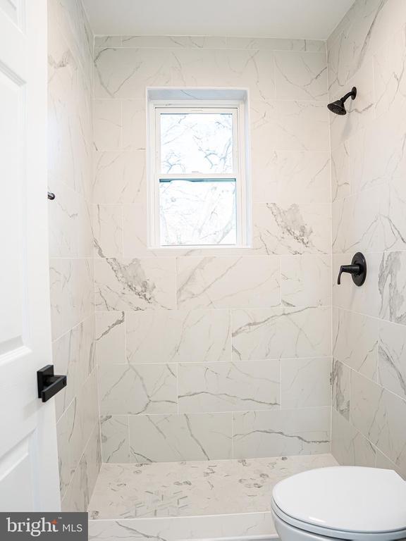 bathroom featuring tiled shower and toilet