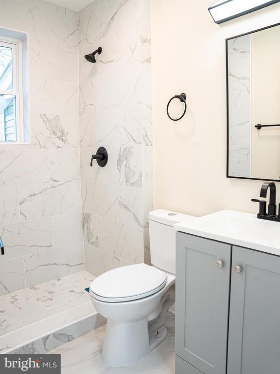 bathroom featuring vanity, toilet, and a tile shower