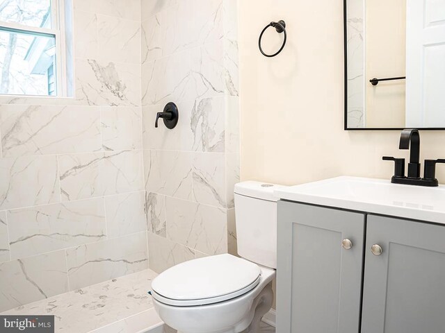 bathroom with vanity, toilet, and a tile shower