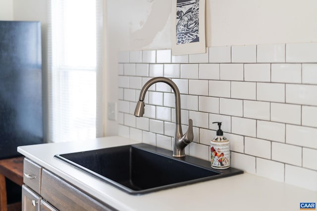 interior details with light countertops, a sink, and decorative backsplash