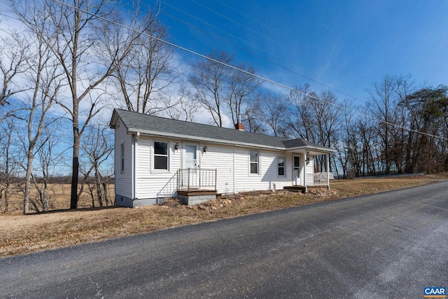 view of front of property featuring a shingled roof, crawl space, and a chimney