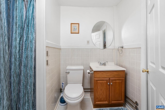 full bathroom featuring toilet, a wainscoted wall, tile walls, and vanity