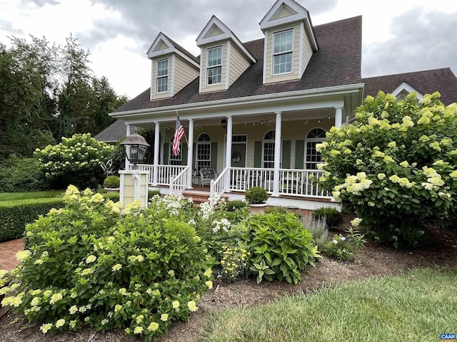 cape cod home featuring covered porch