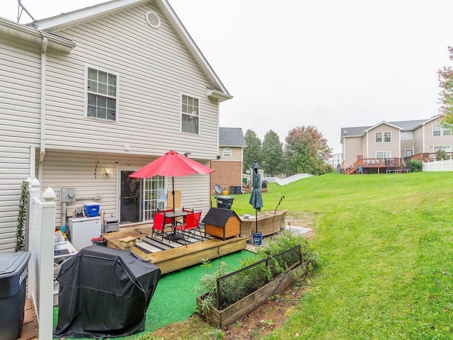 rear view of property featuring a wooden deck and a lawn