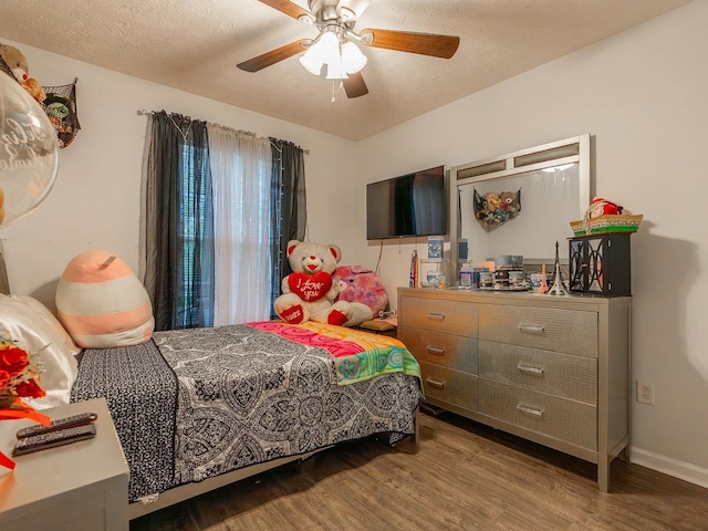 bedroom with ceiling fan, hardwood / wood-style flooring, and a textured ceiling