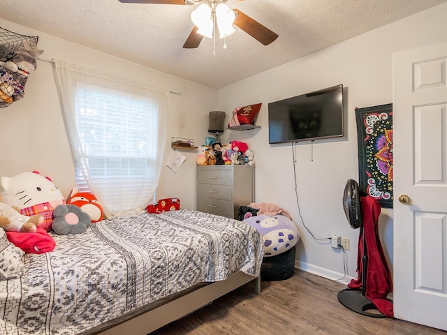 bedroom with ceiling fan, wood-type flooring, and a textured ceiling