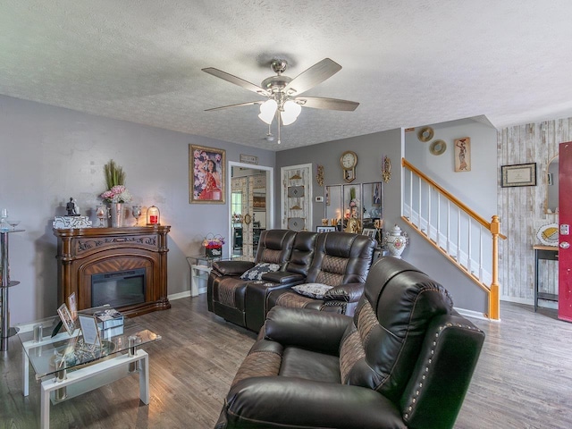 living room featuring wood-type flooring, ceiling fan, and a textured ceiling