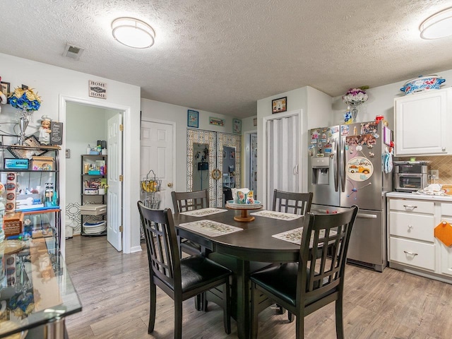 dining room featuring a textured ceiling and light wood-type flooring