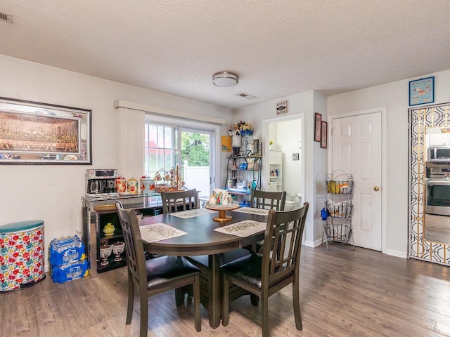 dining space with hardwood / wood-style flooring and a textured ceiling