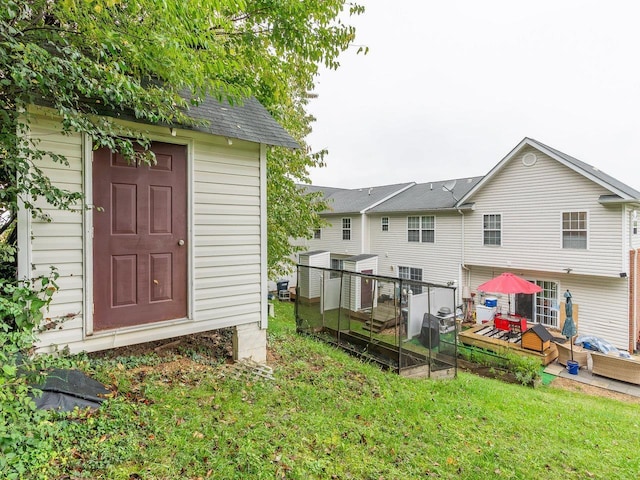 rear view of property featuring a yard, an outbuilding, and a deck