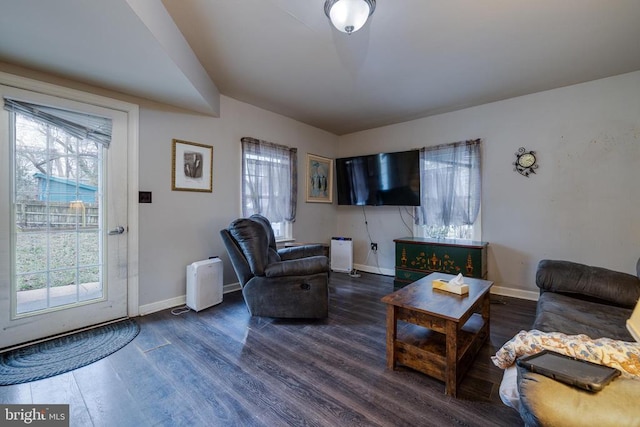 living area featuring a wealth of natural light, baseboards, and dark wood-style flooring