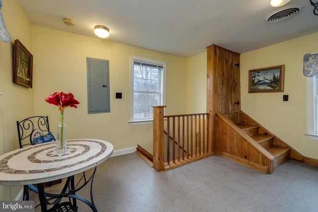 interior space with visible vents, baseboards, electric panel, an upstairs landing, and tile patterned floors