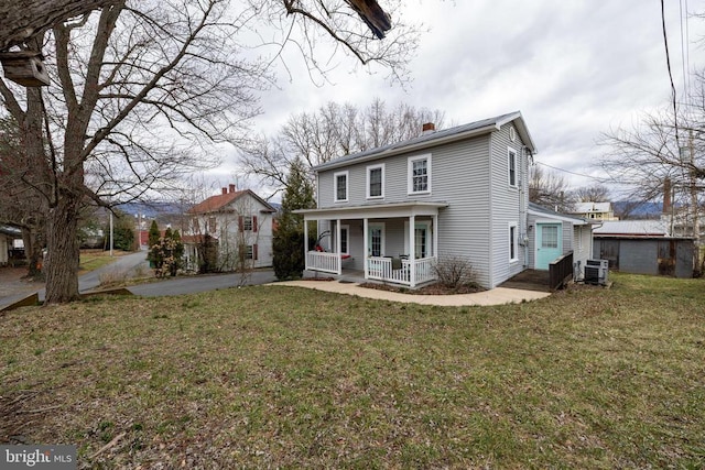 view of front of house featuring central air condition unit, a porch, a chimney, and a front lawn