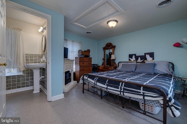 bedroom featuring light floors, visible vents, attic access, a sink, and connected bathroom