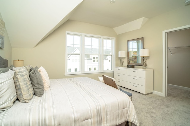 bedroom with vaulted ceiling, a walk in closet, light colored carpet, and a closet