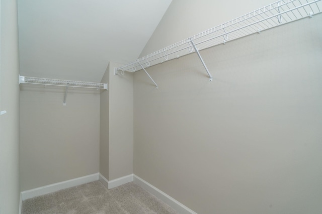 walk in closet featuring light carpet and vaulted ceiling