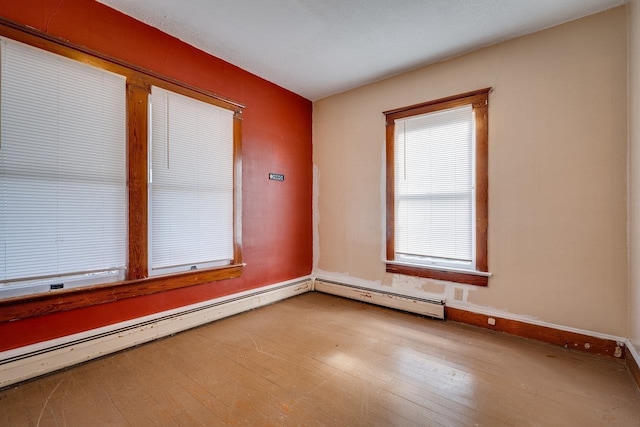 unfurnished room featuring baseboard heating and light hardwood / wood-style flooring