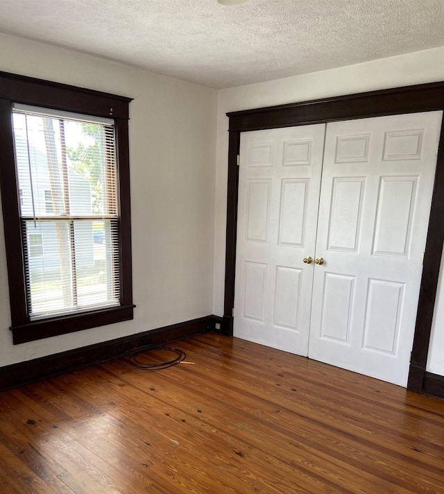 unfurnished bedroom featuring dark wood-type flooring, a textured ceiling, and a closet