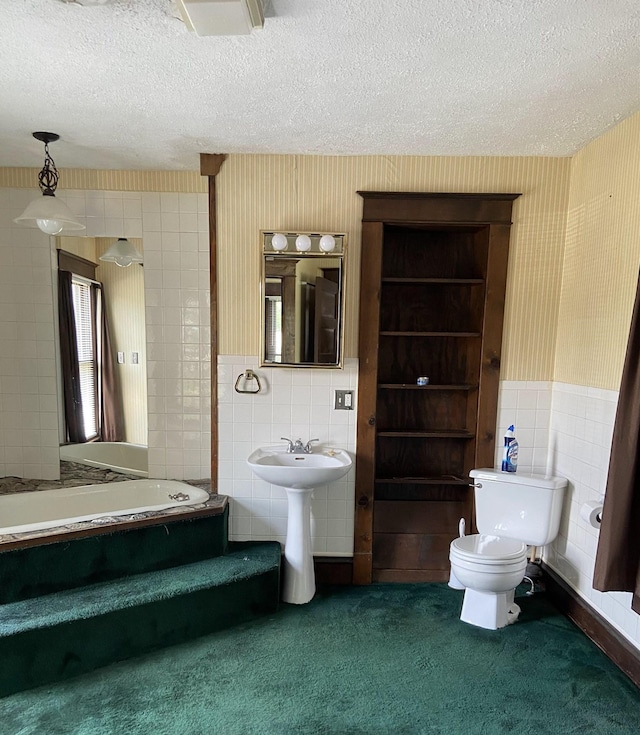 bathroom with a bathtub, tile walls, a textured ceiling, and toilet