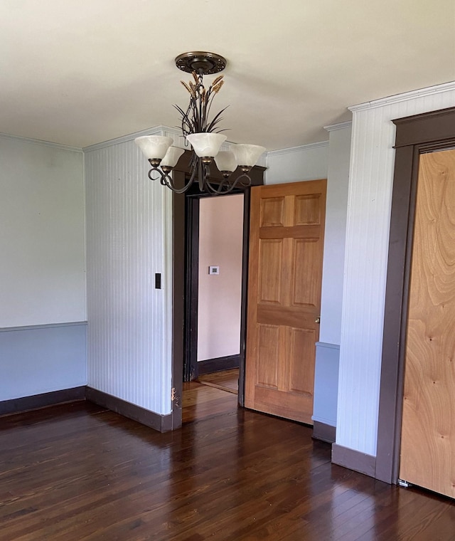 unfurnished dining area featuring ornamental molding, dark hardwood / wood-style floors, and a notable chandelier