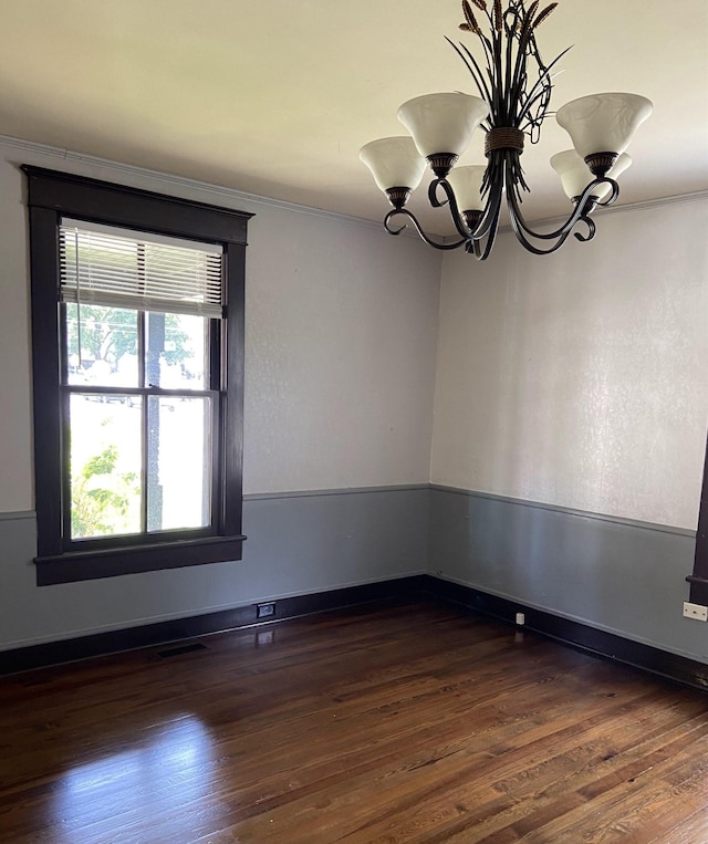 unfurnished room with crown molding, a notable chandelier, and dark hardwood / wood-style flooring