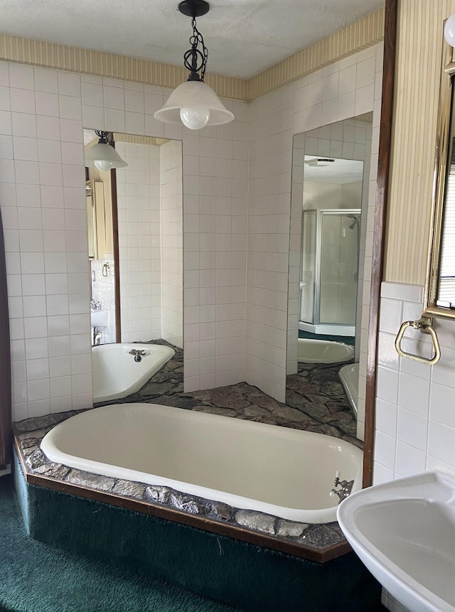 bathroom featuring a shower with shower door, sink, and tile walls