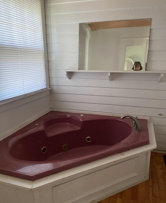 bathroom featuring wooden walls and a bathtub