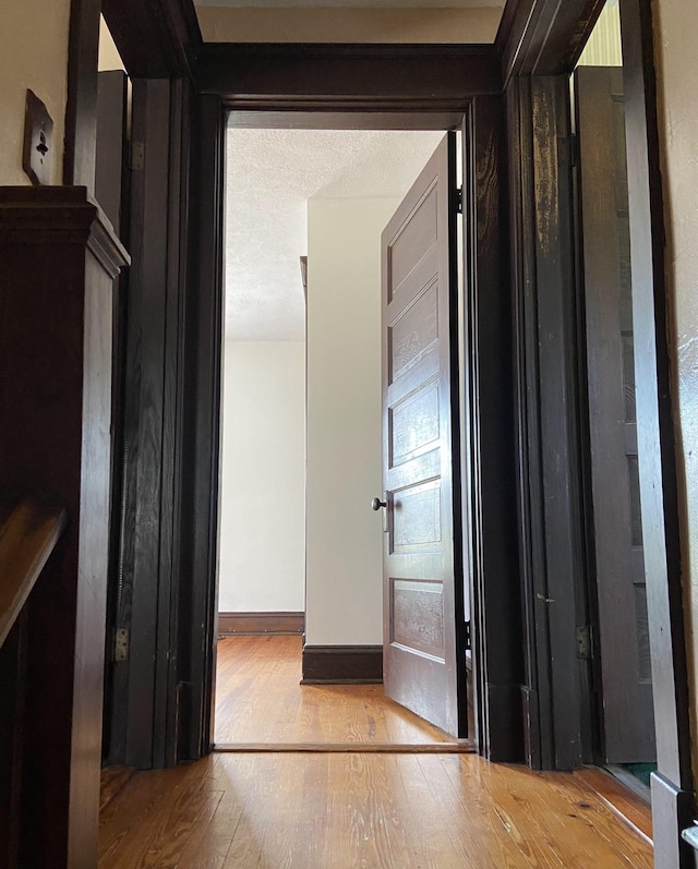 hall featuring light hardwood / wood-style flooring and a textured ceiling