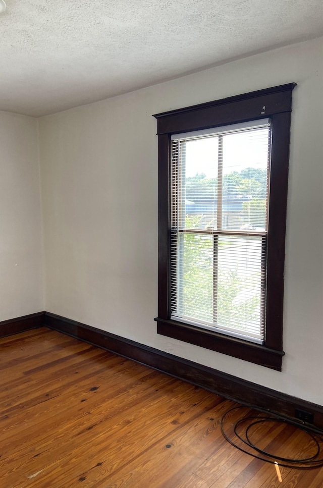 empty room with hardwood / wood-style floors and a textured ceiling