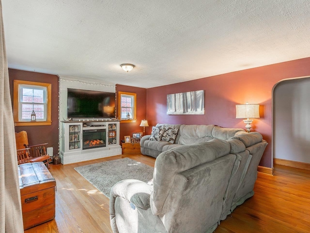 living room featuring plenty of natural light, a fireplace, a textured ceiling, and light wood-type flooring