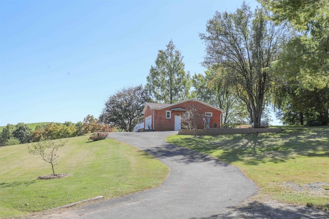 view of side of home featuring aphalt driveway, a lawn, and brick siding