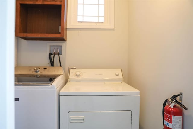 clothes washing area featuring independent washer and dryer and cabinet space