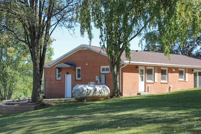 rear view of property featuring a yard and brick siding