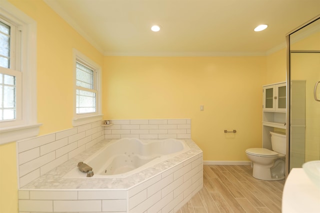 bathroom with baseboards, toilet, a tub with jets, wood finished floors, and crown molding