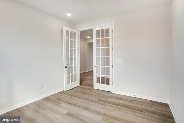 spare room featuring french doors and light wood-type flooring