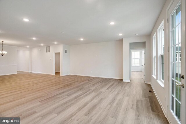 spare room featuring a chandelier and light hardwood / wood-style flooring