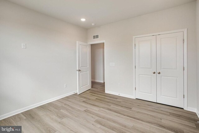 unfurnished bedroom with a closet and light wood-type flooring