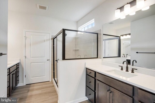 bathroom with wood-type flooring, vanity, and walk in shower