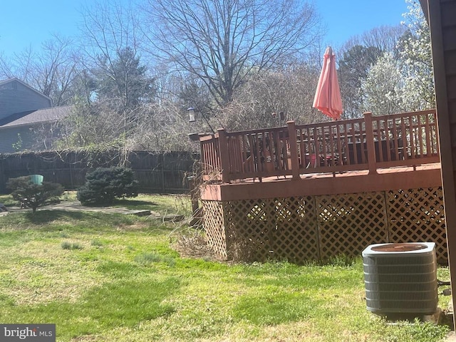 view of yard featuring a deck, fence, and central AC