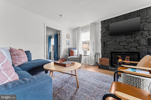 living room with crown molding, a fireplace, and wood finished floors