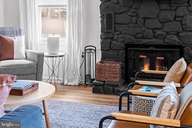 sitting room with visible vents, wood finished floors, and a stone fireplace