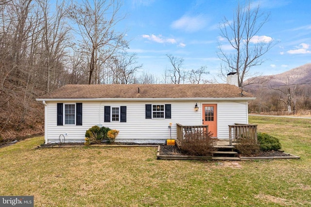 back of house featuring a deck with mountain view, a shingled roof, a chimney, and a yard