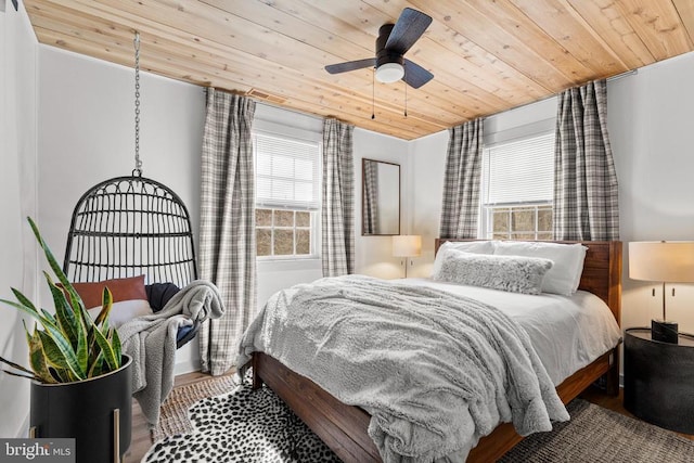 bedroom featuring wood ceiling, multiple windows, a ceiling fan, and wood finished floors