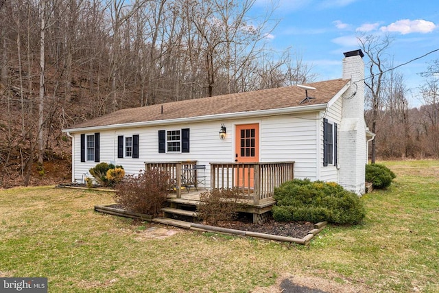 back of house featuring a deck, a yard, a shingled roof, and a chimney