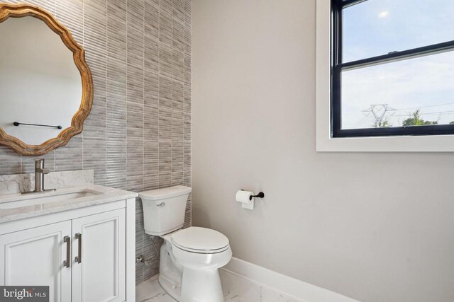 bathroom featuring vanity, tile walls, and toilet