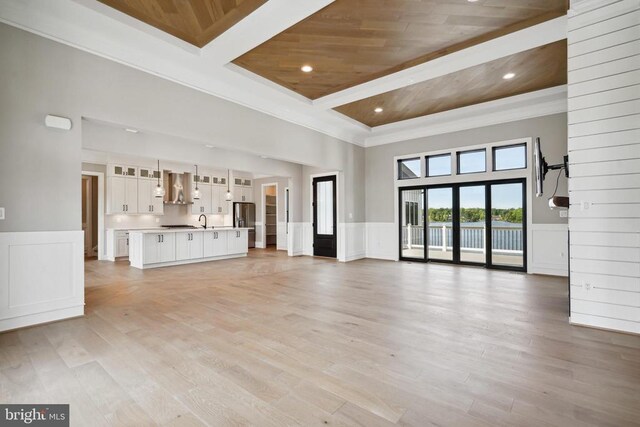 unfurnished living room featuring ornamental molding, a towering ceiling, wood ceiling, and light wood-type flooring