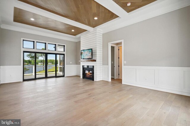 unfurnished living room featuring a large fireplace, ornamental molding, light hardwood / wood-style floors, and wooden ceiling