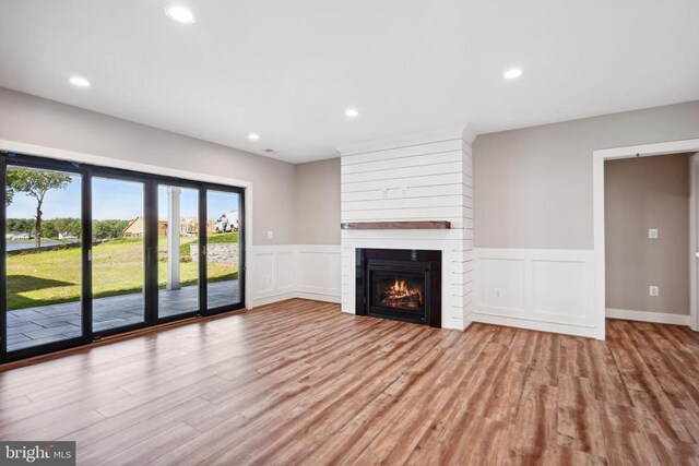 unfurnished living room with a large fireplace and light hardwood / wood-style floors