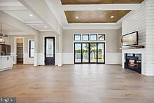 unfurnished living room featuring a large fireplace, coffered ceiling, hardwood / wood-style floors, and beam ceiling