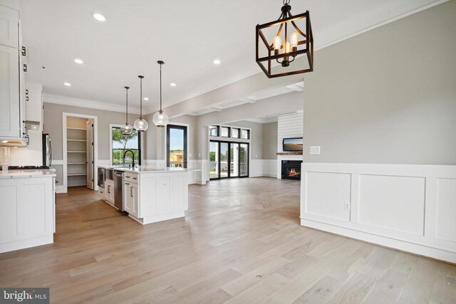 kitchen featuring a healthy amount of sunlight, a kitchen island with sink, hanging light fixtures, and white cabinets